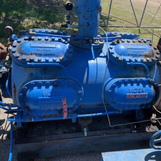Blue industrial booster pump with two connected housings mounted on a metal frame, outdoors, with pipes, valves, and rusted supports visible.