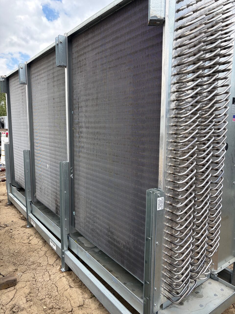 Large outdoor industrial heat exchanger with multiple finned panels mounted in a metal frame.