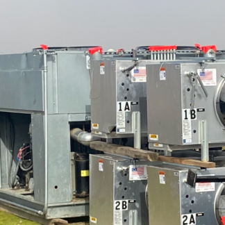 Row of industrial HVAC units with labeled panels (1A, 1B, 2A, 2B) and exposed piping on a concrete surface in an outdoor setting.