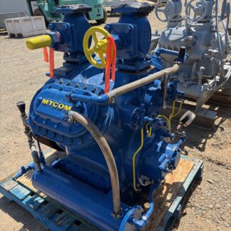 Blue MYCOM industrial pump on a wooden pallet outdoors, with a yellow handwheel and connected hoses and valves