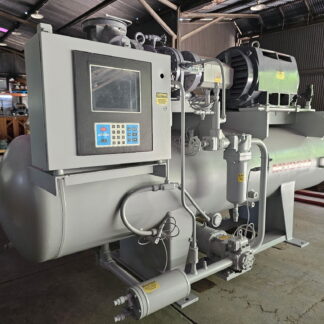 Large industrial machine with control panel, pipes, and a big green motor in a warehouse setting.