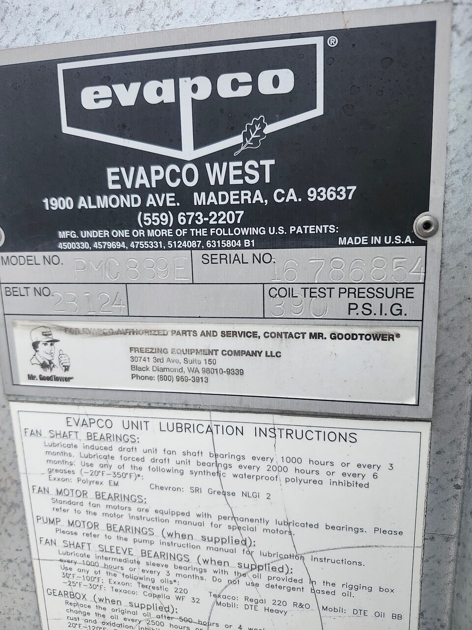 Close-up of an Evapco West equipment data plate showing company logo, address, phone number, and serial/model details.