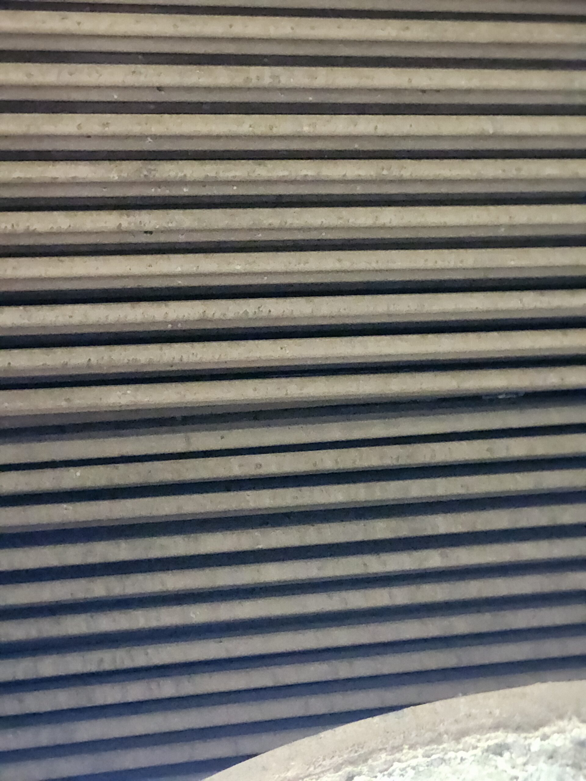 Close-up of dusty horizontal metal slats forming a vent or shutter pattern.