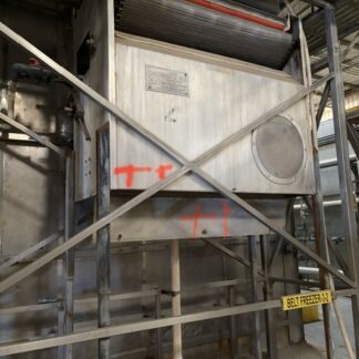 Industrial belt-freezer unit on a metal scaffold with an orange conveyor belt visible at the top and plumbing beneath; has red graffiti and a yellow tag reading Belt Freezer 3.