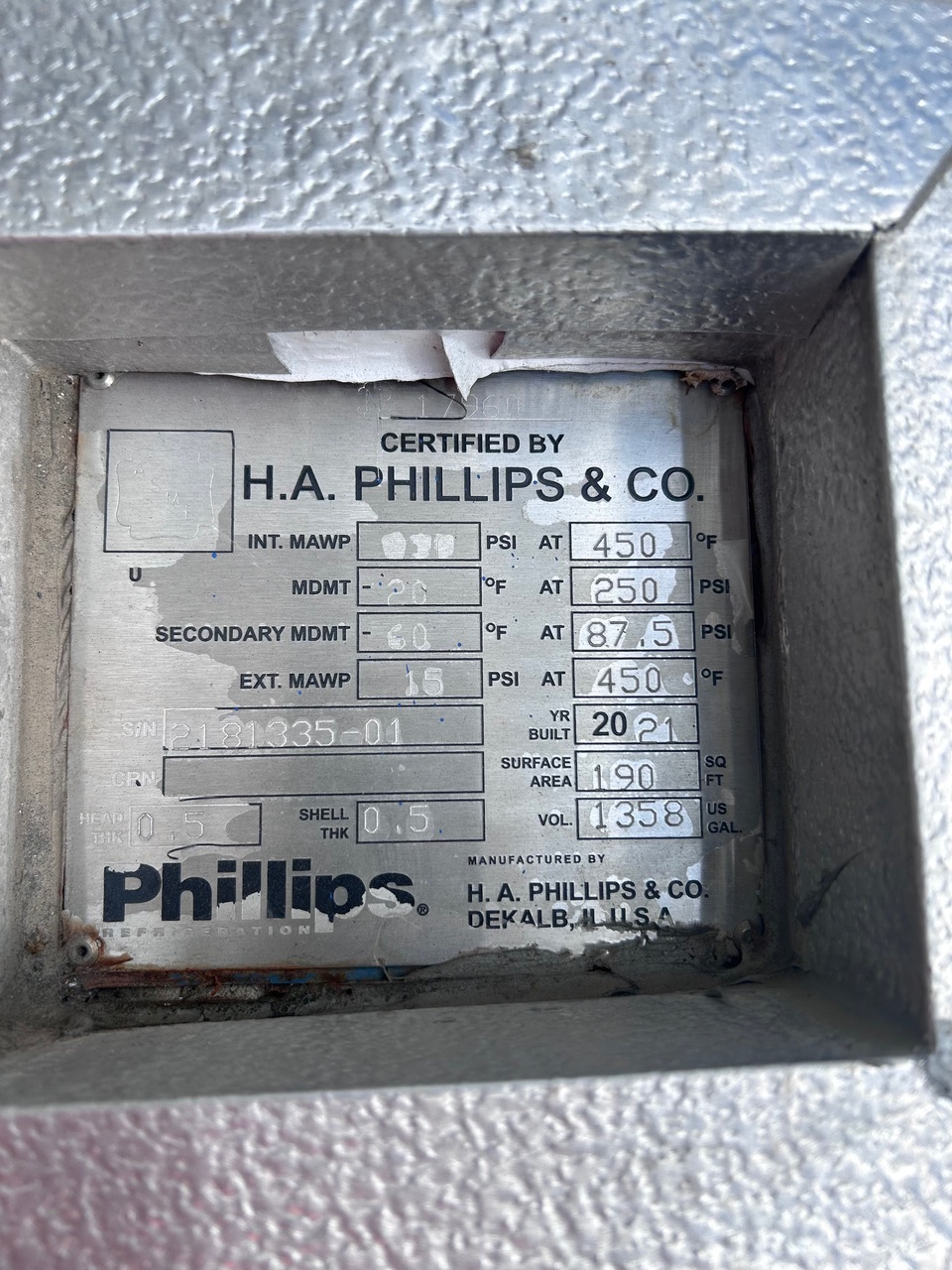 Close-up of a metal certification plate reading 'H.A. Phillips & Co.' with equipment specs and build year 2021 on a textured surround