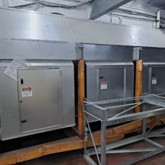 Industrial HVAC ductwork and metal equipment mounted on wooden supports in a mechanical room, with exposed wiring overhead and warning labels on doors.