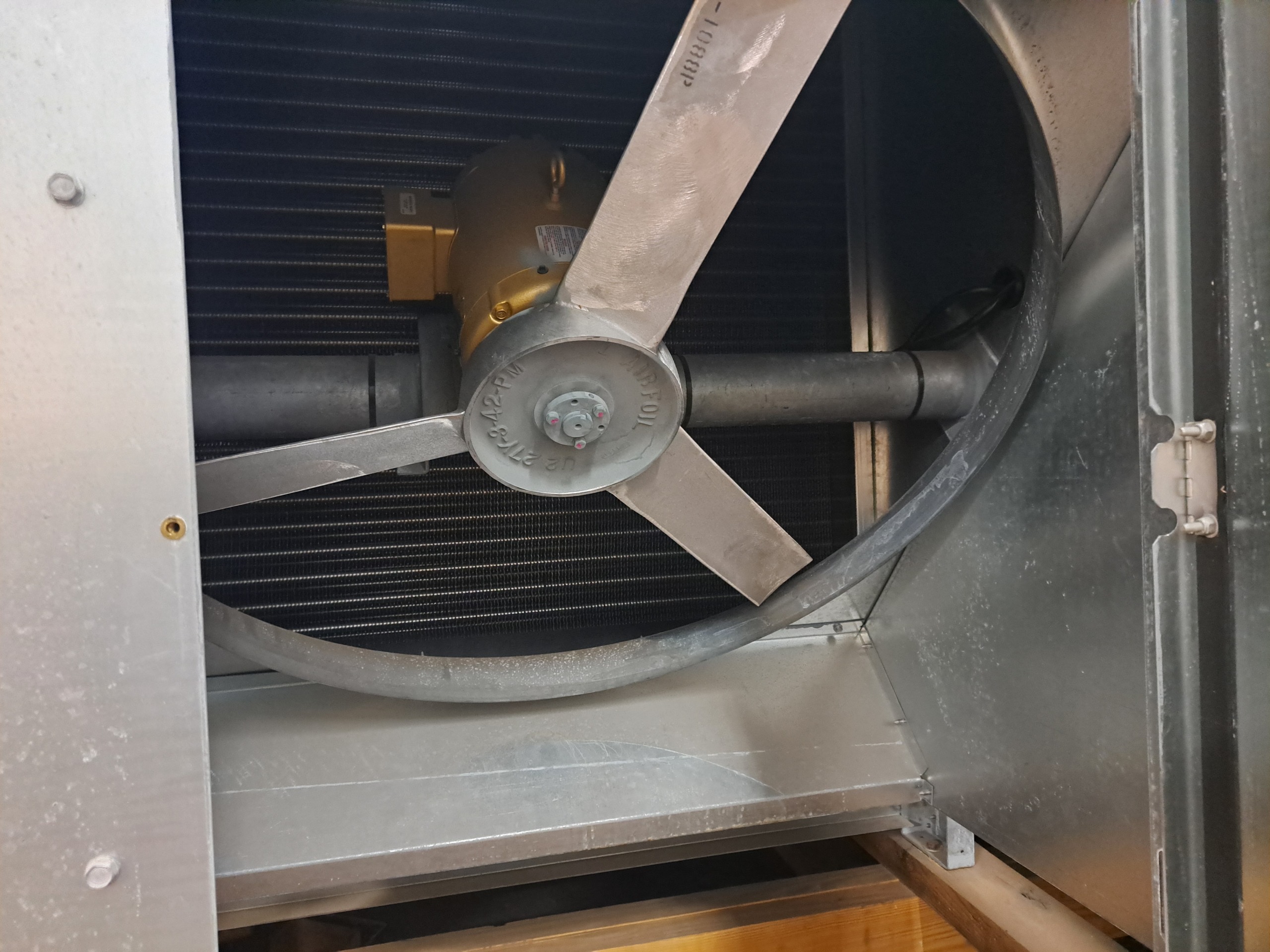 Industrial air handling unit: metal housing with a large circular blower wheel and angled blades, and a gold-colored motor behind it.