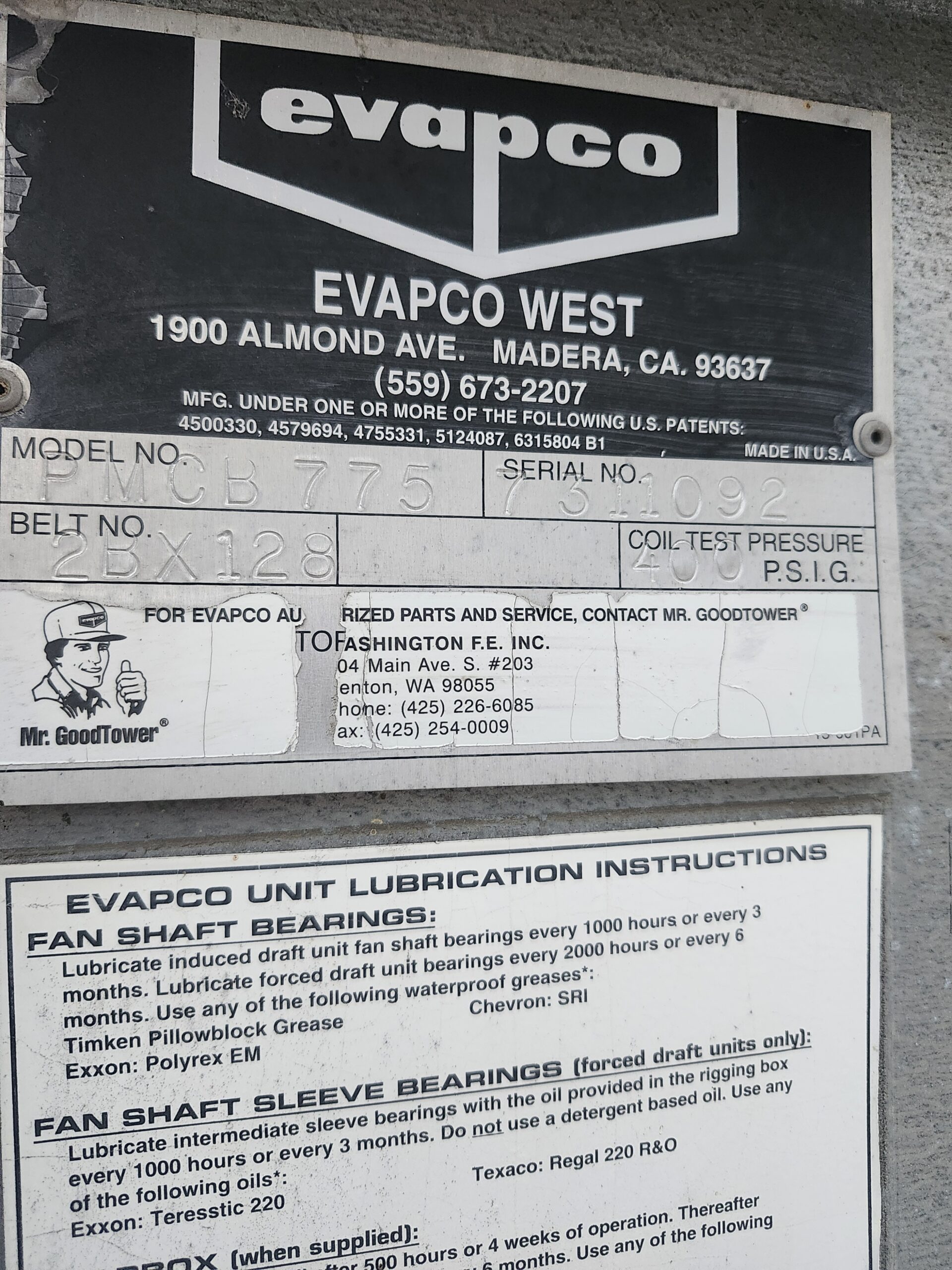 Metal nameplate on an industrial unit showing EVAPCO West branding, model/serial numbers, belt size, and lubrication instructions.