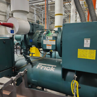 Large Frick generator in a mechanical room with pipes, control panel, and warning labels visible.