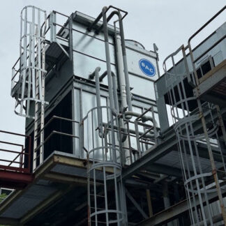 Industrial processing facility with metal framework, ladders, and interconnected pipes; a gray unit bears a blue BRC logo.