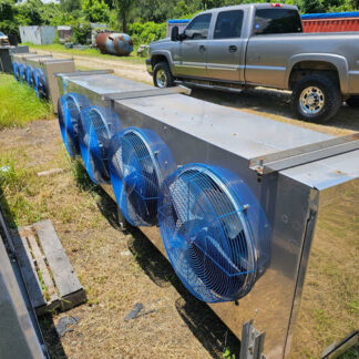 Row of large blue industrial cooling fans mounted on a shiny stainless steel enclosure outdoors, with a pickup truck in the background.