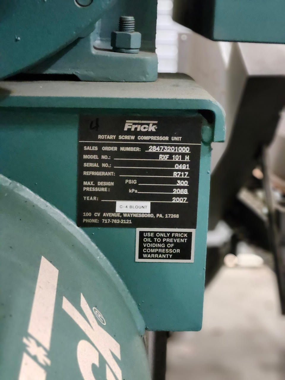 Close-up of a Frick rotary screw compressor unit nameplate with model RXF 101H and serial number 0491.