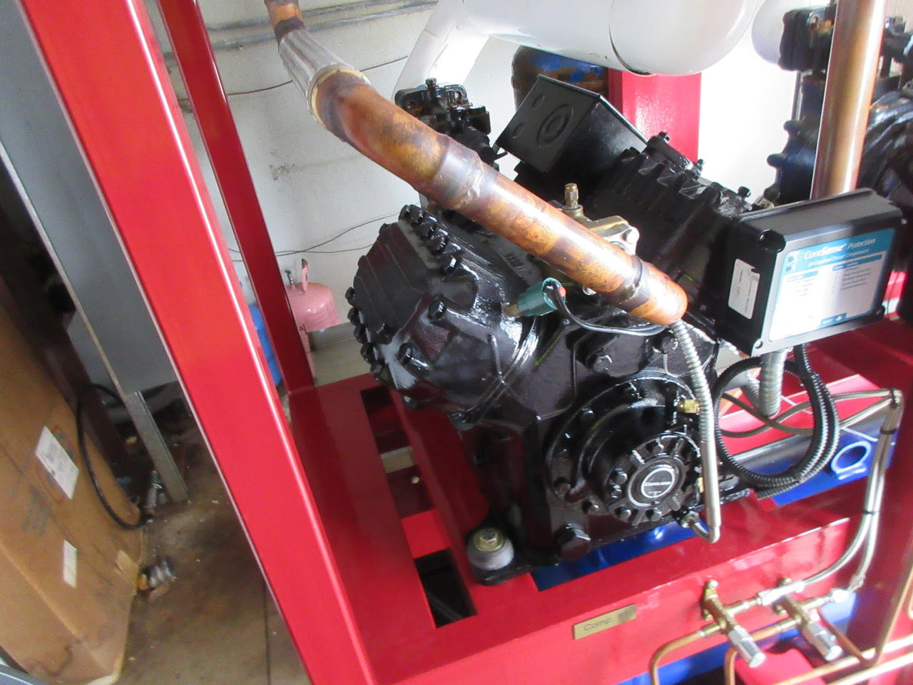 Industrial engine mounted on a red frame with copper exhaust pipe and control box nearby