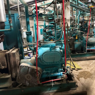 Industrial mechanical room with teal pumps, a network of pipes, and red lifting straps surrounding the equipment.