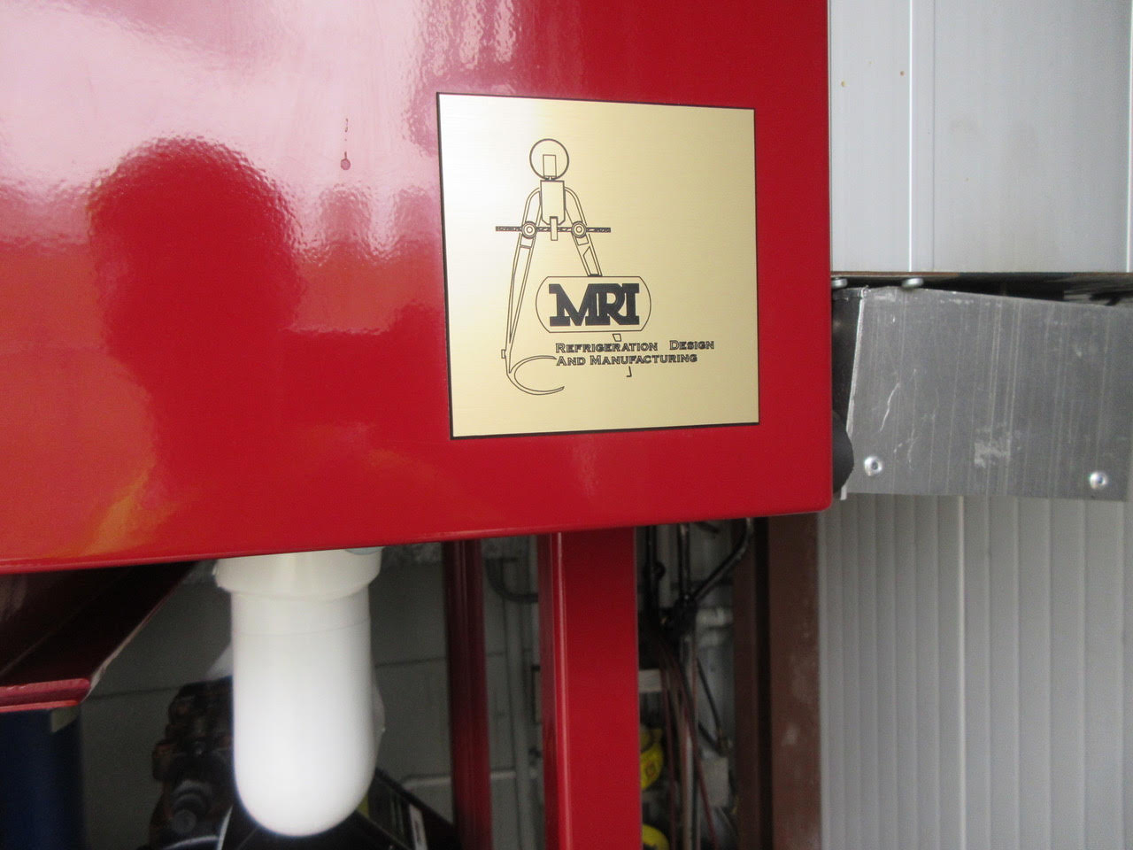 Red industrial machine with a gold plaque that reads 'MRI Refrigeration Design and Manufacturing'.