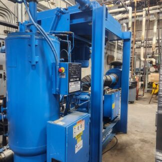 Blue industrial chiller with a vertical tank and complex piping in a mechanical room, part of the cooling system.