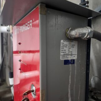 Auto-Purger unit in a mechanical room: red panel, grey body, key in the lock, and a data plate visible.