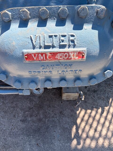 Close-up of a blue industrial valve cover with large bolts, embossed 'VILTER' and a red plate reading 'VMC 450XL'.