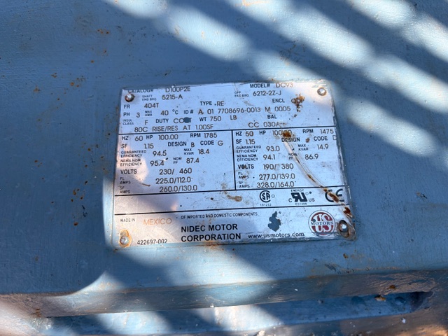 Close-up of a weathered blue motor nameplate attached to a machine, showing model and electrical specs from Nidec Motor Corporation.