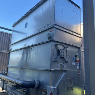 Large outdoor metal HVAC air handling unit with a circular fan and ductwork on a rooftop.