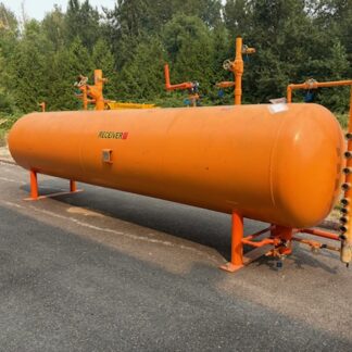 Large orange horizontal pressurized storage tank with valves and gauges on supports beside a paved lot, labeled 'RECEIVER'.